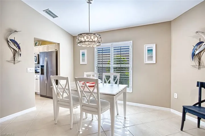 Tiled dining space with lofted ceiling and a notable chandelier