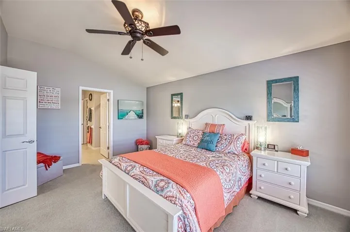 Bedroom with light colored carpet, vaulted ceiling, and ceiling fan