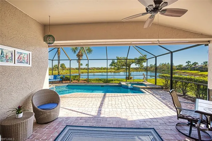 View of swimming pool with ceiling fan, a lanai, a patio area, an in ground hot tub, and a water view