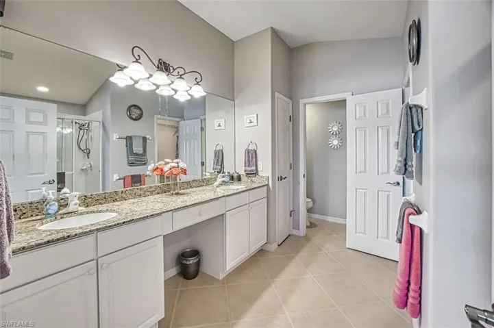 Bathroom with tile patterned flooring, vanity, an enclosed shower, and toilet