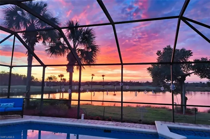 Pool at dusk with a water view and glass enclosure