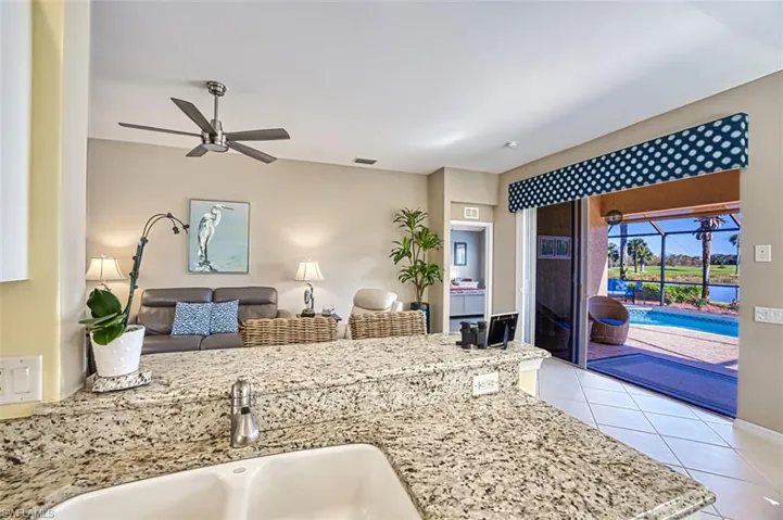 Kitchen featuring ceiling fan, light stone counters, light tile patterned floors, and sink