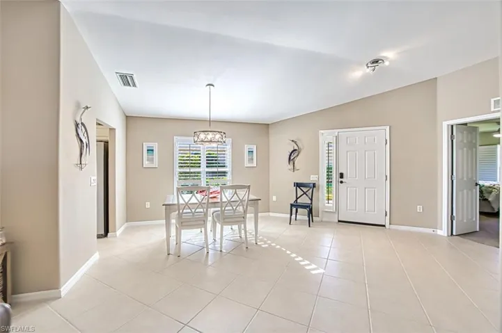 Dining room featuring lofted ceiling, light tile patterned floors, and a chandelier