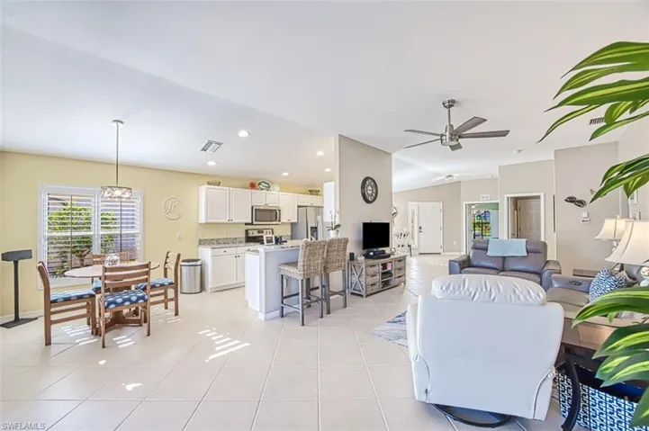 Tiled living room featuring ceiling fan and lofted ceiling