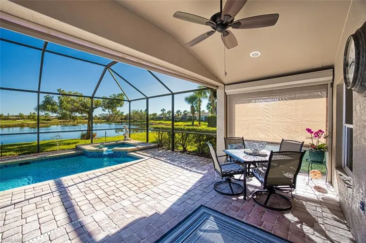 View of swimming pool featuring a water view, ceiling fan, a lanai, an in ground hot tub, and a patio area