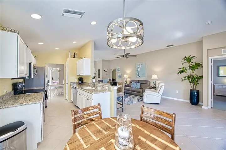 Dining area featuring ceiling fan with notable chandelier, light tile patterned flooring, lofted ceiling, and sink