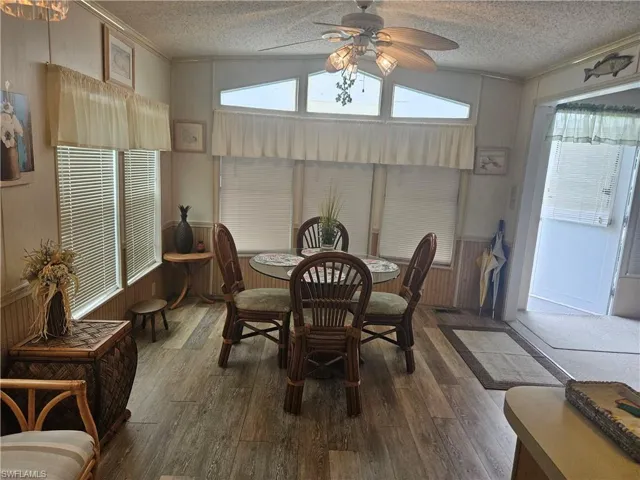 Dining area with hardwood / wood-style floors, vaulted ceiling, a textured ceiling, and ceiling fan