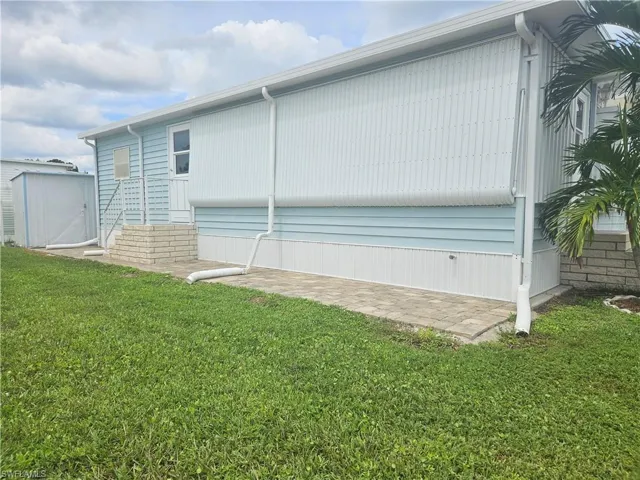 View of property exterior with a lawn and a storage unit
