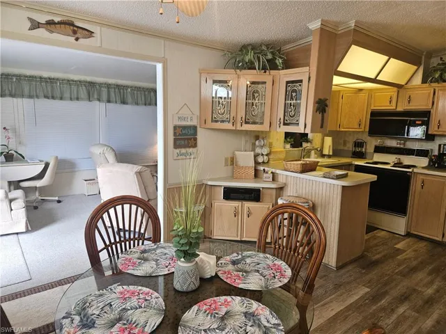 Dining area featuring dark hardwood / wood-style flooring, a textured ceiling, sink, and crown molding