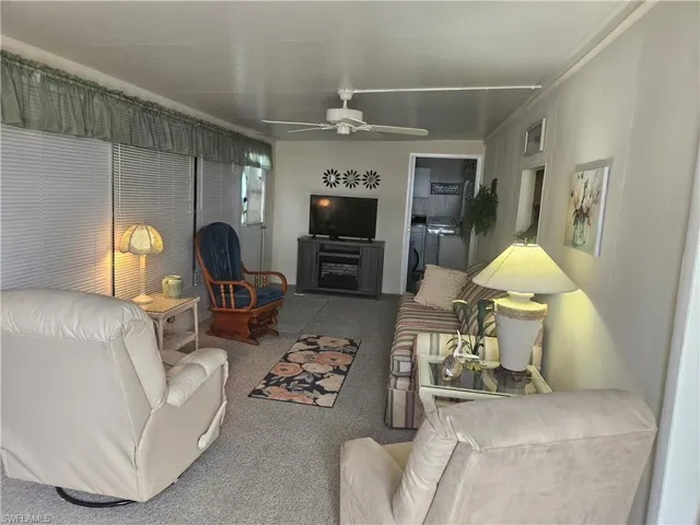 Living room featuring a fireplace, carpet floors, ceiling fan, and washer and dryer