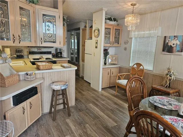 Kitchen featuring kitchen peninsula, dark wood-type flooring, white appliances, and a textured ceiling