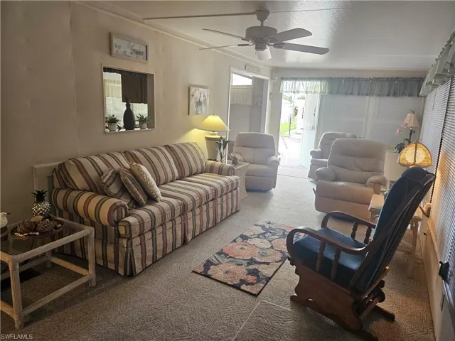 Living room with ceiling fan, carpet, and a textured ceiling