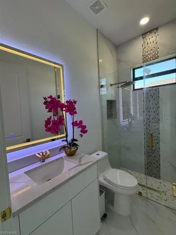 Bathroom with vanity, toilet, a shower with door, and tile patterned flooring
