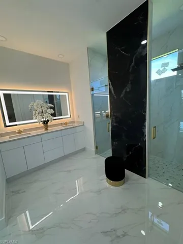 Bathroom with double sink vanity, tile patterned flooring, and a shower with shower door