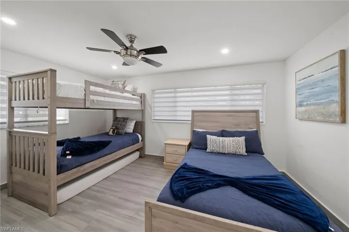 Bedroom featuring wood-finish flooring, recessed lighting, a brushed-nickel ceiling fan, and horizontal window shades