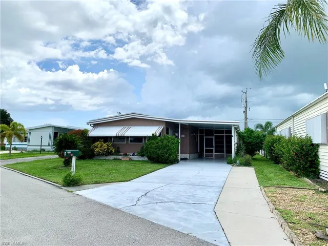 View of front of property with a carport and a front yard