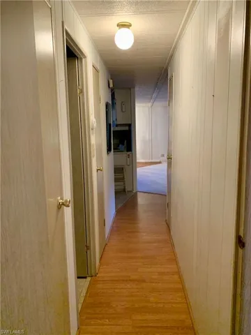 Corridor with light hardwood / wood-style flooring and a textured ceiling