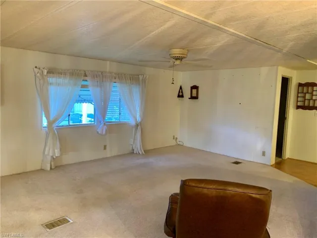 Carpeted living room featuring ceiling fan