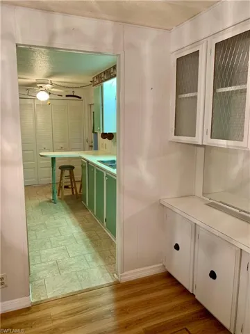 Kitchen with green cabinets, ceiling fan, white cabinets, and light hardwood / wood-style floors