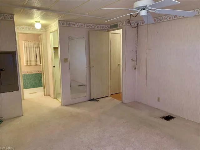 Unfurnished bedroom with ensuite bathroom, light carpet, ceiling fan, and electric panel