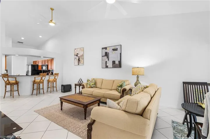 Living area featuring light tile patterned flooring, a ceiling fan, high vaulted ceiling, and recessed lighting