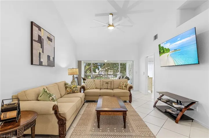 Living area featuring light tile patterned flooring, high vaulted ceiling, and a ceiling fan