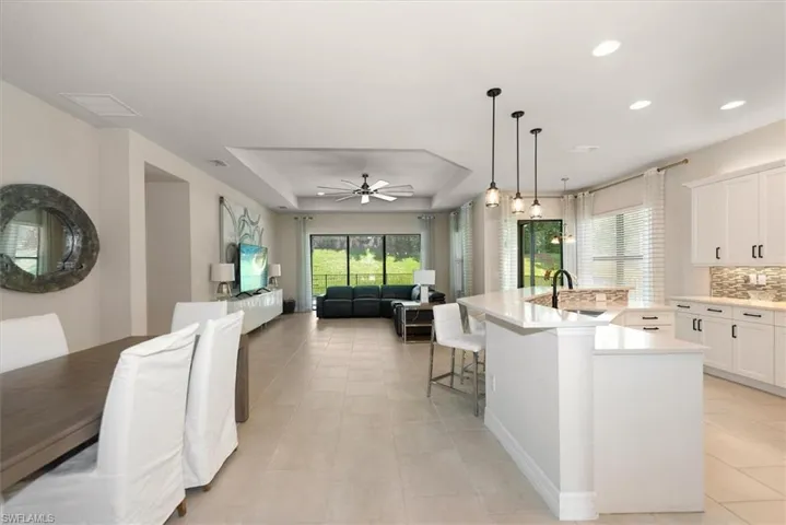 Kitchen featuring tasteful backsplash, ceiling fan, a tray ceiling, open floor plan, and light countertops