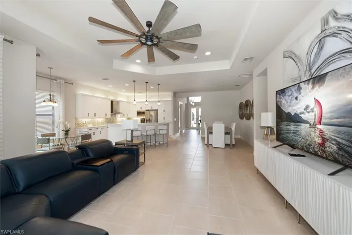 Kitchen with open floor plan, stainless steel appliances, recessed lighting, light tile patterned floors, and wall chimney range hood