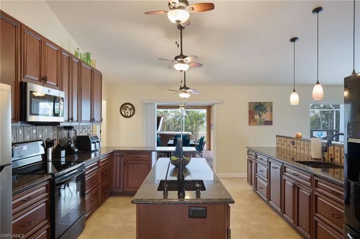Kitchen with a center island, sink, black electric range, dark stone countertops, and pendant lighting
