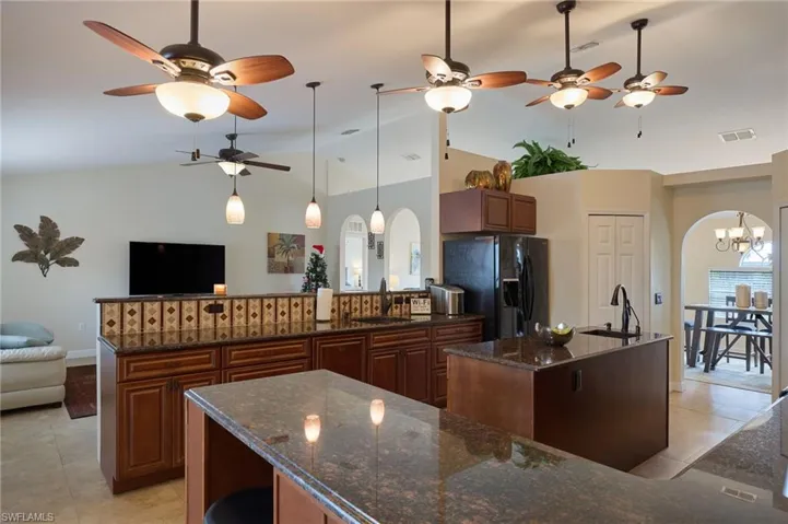 Kitchen with a center island, sink, an inviting chandelier, lofted ceiling, and black fridge with ice dispenser