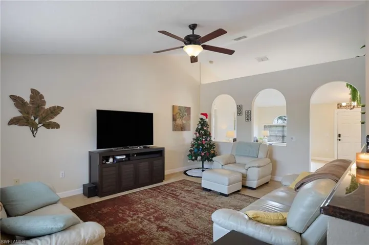 Tiled living room with ceiling fan and vaulted ceiling