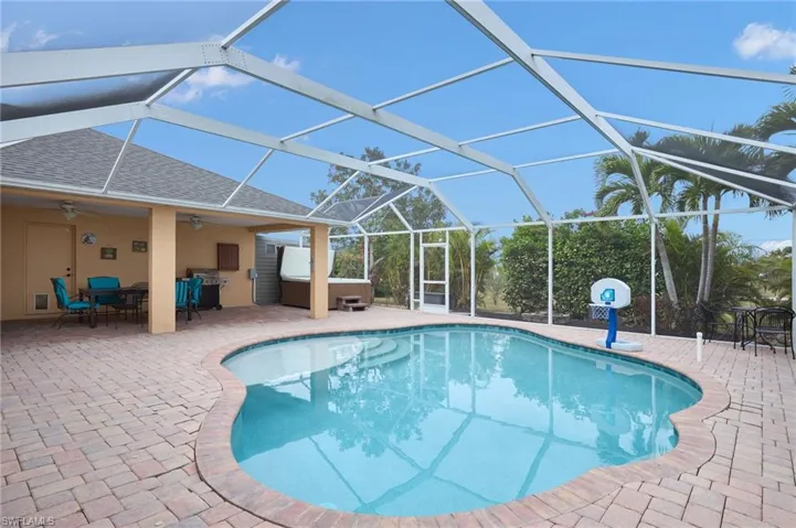 View of swimming pool featuring a hot tub, glass enclosure, ceiling fan, and a patio area