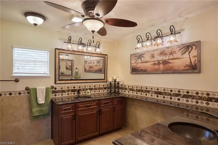 Bathroom with vanity, tile patterned floors, tile walls, and ceiling fan