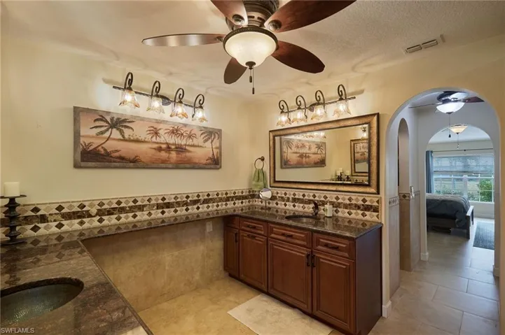 Bathroom with vanity, tile patterned floors, ceiling fan, a textured ceiling, and tile walls