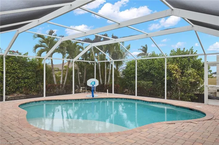View of swimming pool with glass enclosure and a patio