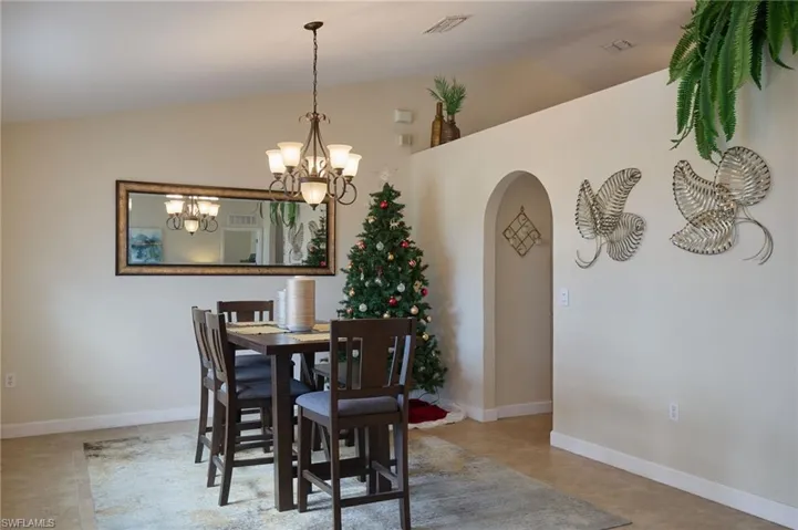 Tiled dining space with lofted ceiling and a chandelier