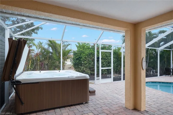 Unfurnished sunroom featuring a healthy amount of sunlight and a pool with hot tub