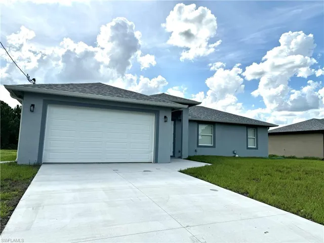 Single story home with a garage and a front lawn