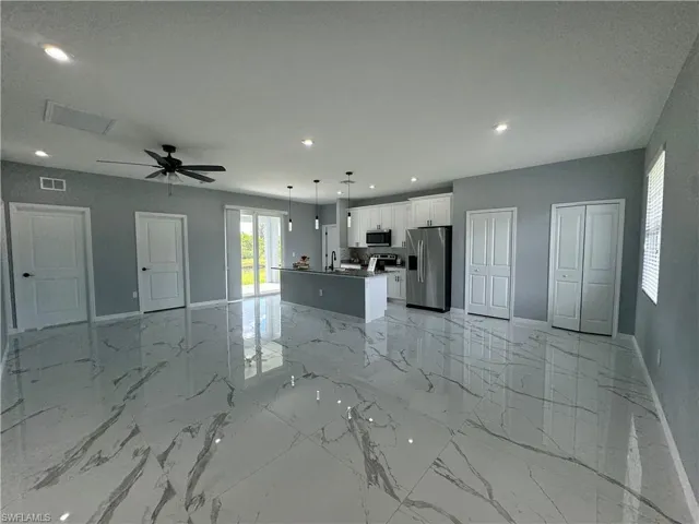 Kitchen with white cabinetry, light tile patterned floors, a center island, stainless steel appliances, and hanging light fixtures