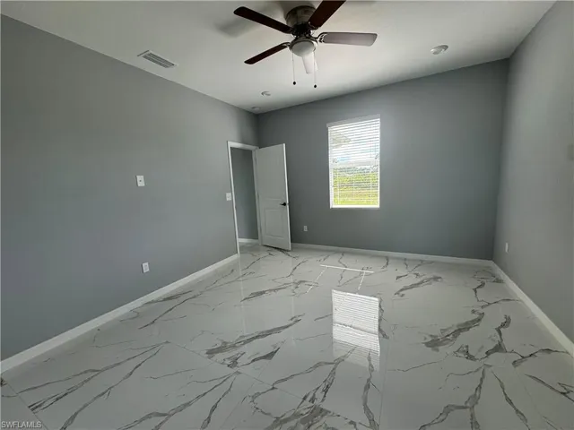 Tiled spare room featuring ceiling fan
