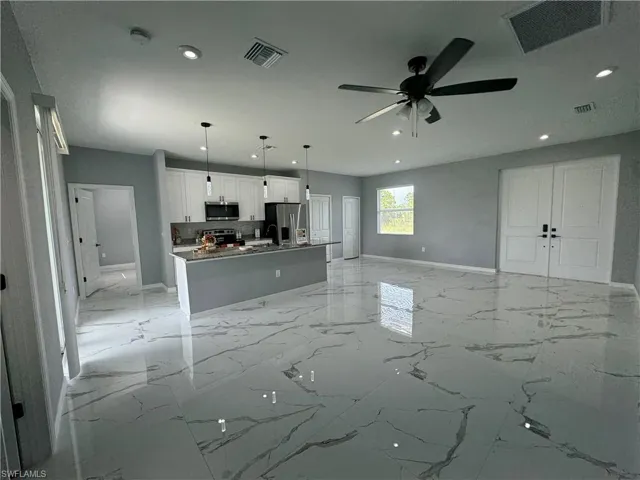 Kitchen with light tile patterned flooring, white cabinetry, ceiling fan, stainless steel appliances, and hanging light fixtures