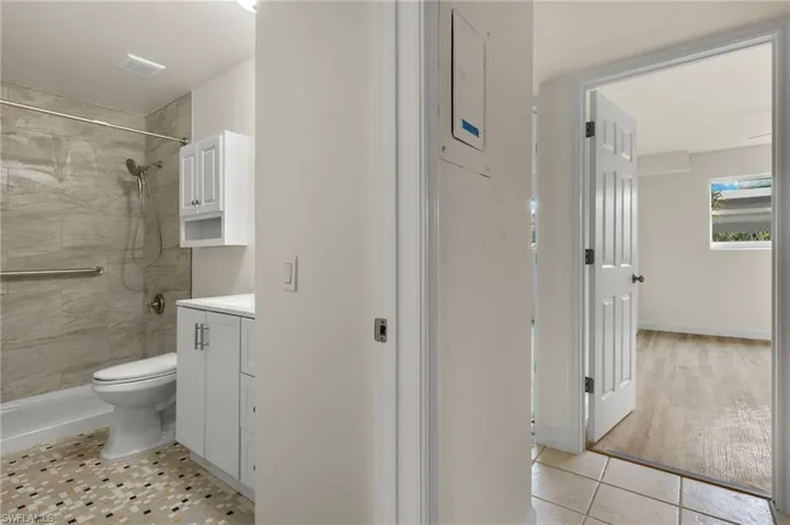 Bathroom featuring tile patterned floors, vanity, a tile shower, and toilet