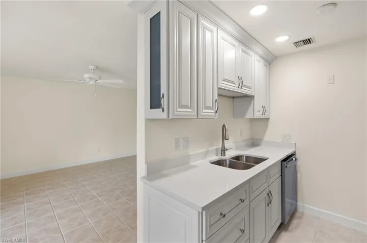 Kitchen with ceiling fan, sink, light tile patterned floors, and white cabinets