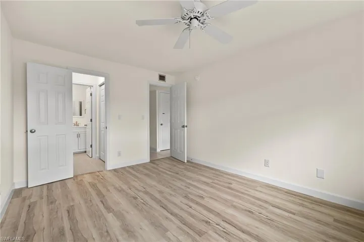 Unfurnished bedroom with ceiling fan, ensuite bath, and light hardwood / wood-style floors