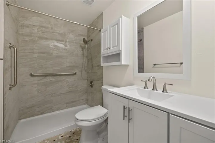 Bathroom featuring tile patterned floors, a tile shower, vanity, and toilet