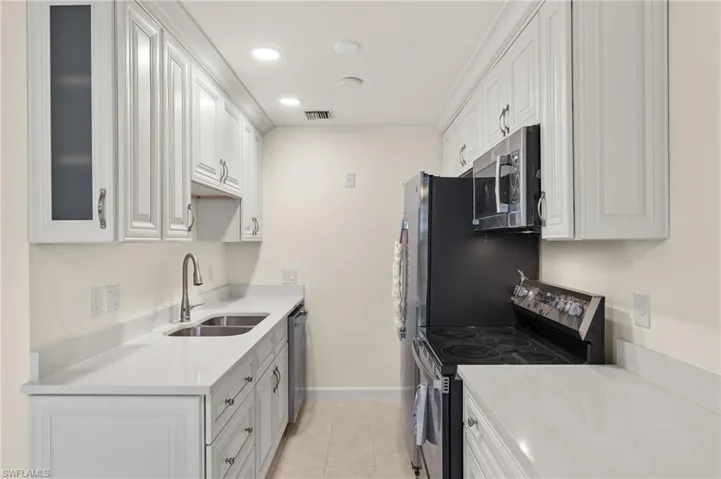 Kitchen featuring light tile patterned flooring, appliances with stainless steel finishes, sink, and white cabinetry