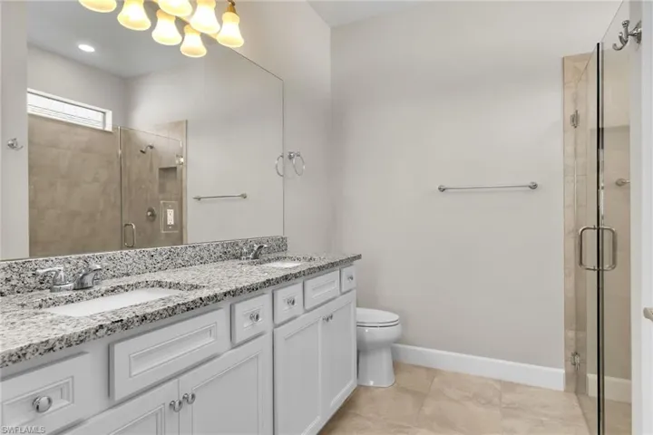 Full bath with double vanity, a shower stall, and light tile patterned floors