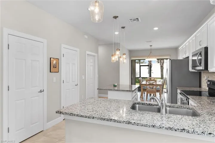 Kitchen featuring white cabinetry, hanging light fixtures, stainless steel appliances, light stone counters, and recessed lighting