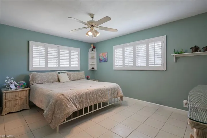Bedroom with multiple windows, light tile patterned floors, and a ceiling fan