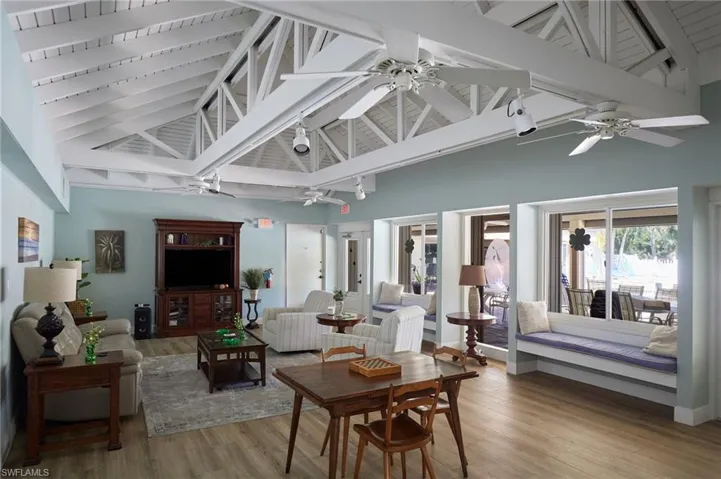 Living area with high vaulted ceiling, wood finished floors, and beam ceiling